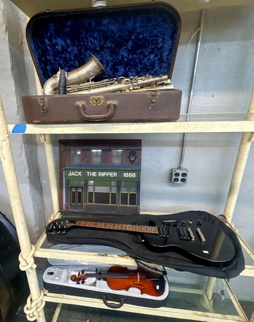 Vintage saxophone in case, black electric guitar and violin in case