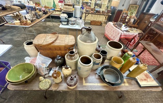 Salt-glazed stoneware crocks and jugs, cast iron skillets and a picnic basket