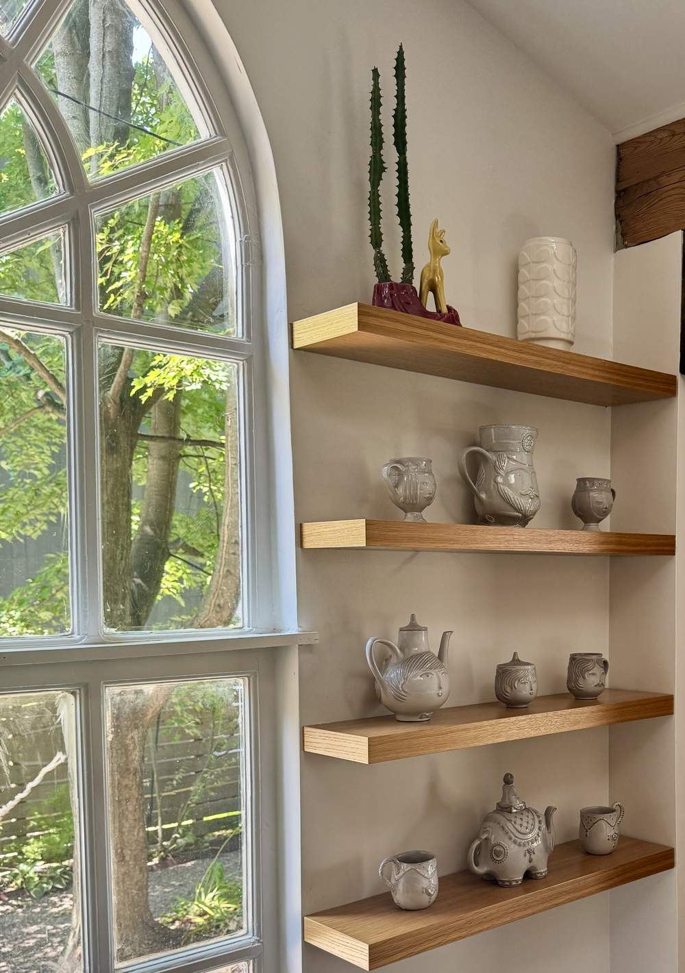 Floating shelves with face-motif ceramic mugs and teapots
