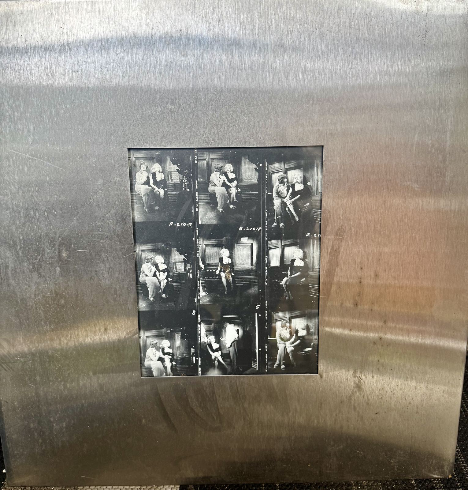 Framed black and white contact sheet, film stills mounted on brushed steel