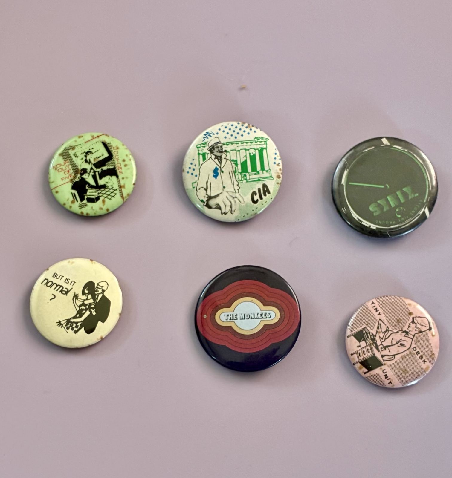 Set of six vintage pinback buttons, including CIA and Monkees designs